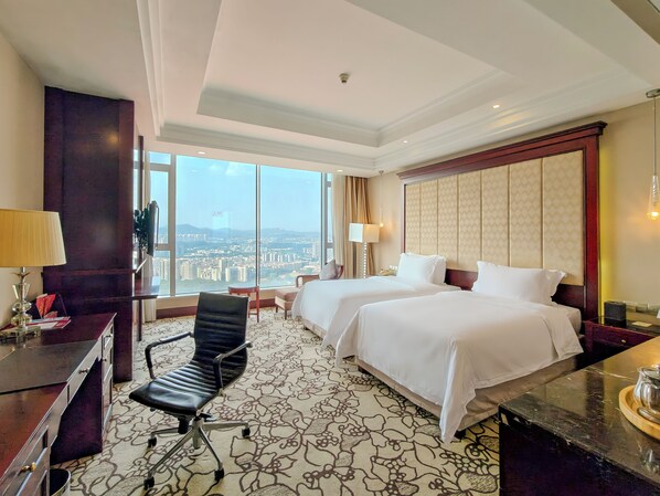 A hotel room with two beds, a desk, a chair, and a large window offering a city view. - Soluxe Hotel Guangzhou (Guangzhou)