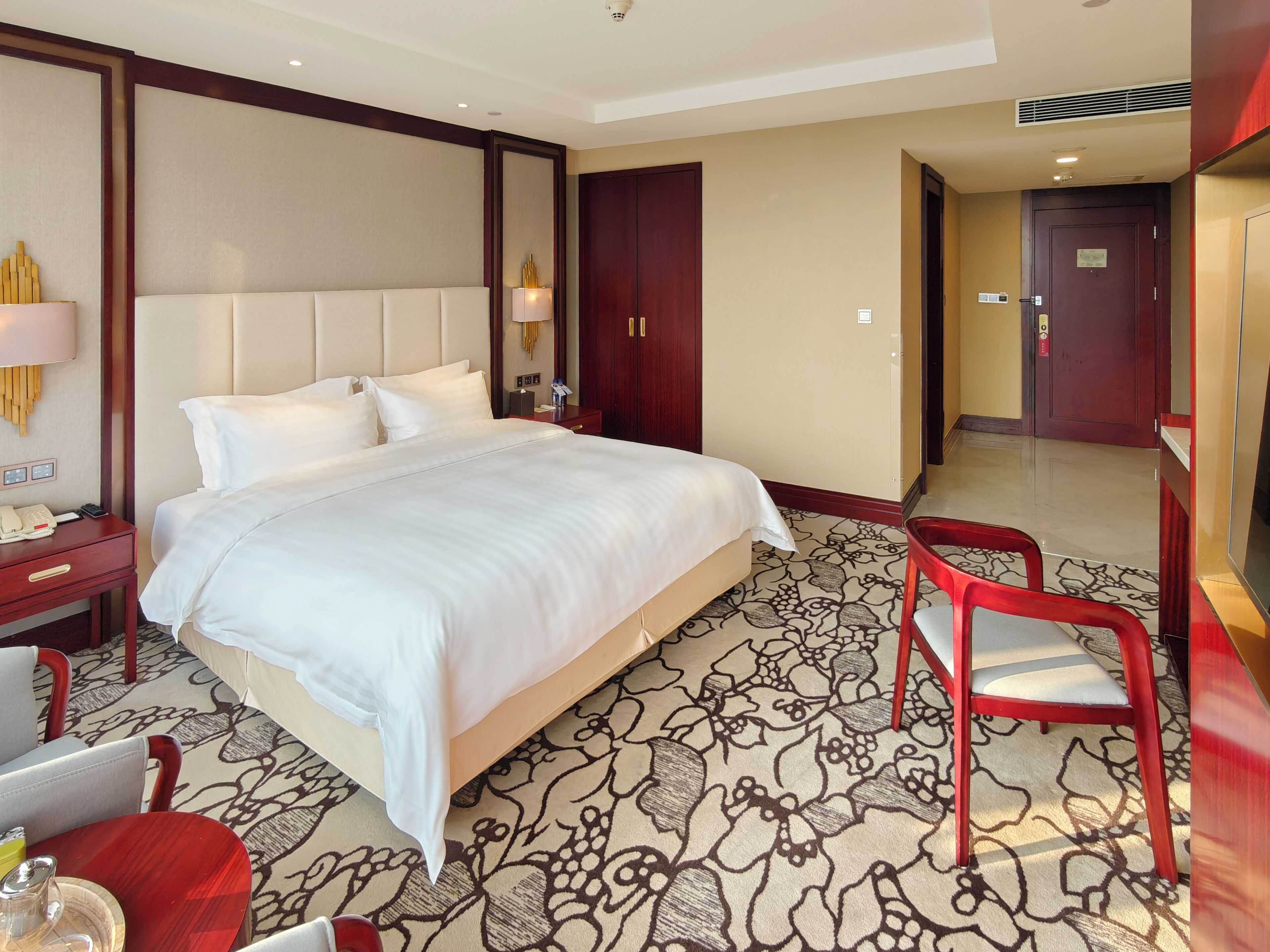 Une chambre d’hôtel avec un grand lit, un bureau avec un téléphone, une chaise et une lampe de bureau.