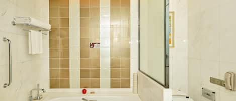 Ein modernes Badezimmer mit Badewanne, Toilette und Haltegriffen.