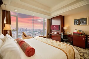 Camera d'albergo con un letto grande, una scrivania, una sedia, una televisione e vista sulla città.