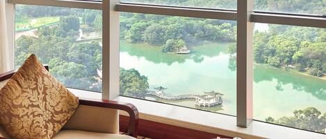 A room with a large window offering a view of a lake, a bridge, and surrounding greenery.