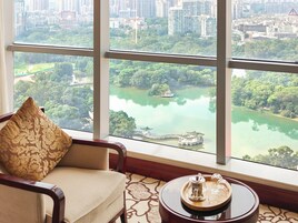 A room with a large window offering a view of a lake, a bridge, and surrounding greenery.