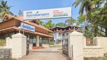 A hotel entrance with a sign for KTDNANDAM, featuring rooms, restaurant, and conference hall.