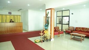 A reception area with a wooden desk, red sofas, and a decorative pillar. - KTDC Nandanam Guruvayoor (Chavakkad)