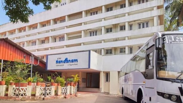 A multi-story building with a sign for "Handanam" hotel. A white bus is parked in front. - KTDC Nandanam Guruvayoor (Chavakkad)
