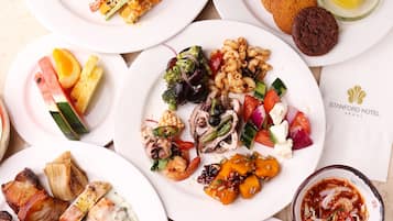 Verschiedene Gerichte auf Tellern, darunter Sushi, Salate und Desserts.