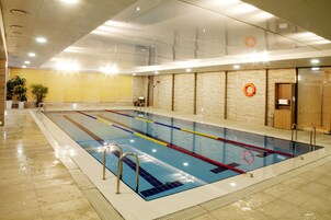 Una piscina cubierta con carriles claramente delimitados, una silla de salvavidas y una puerta de madera.