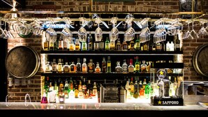 A bar with multiple shelves of liquor bottles, a Sapporo sign, and hanging glasses. - Stanford Hotel Seoul (Seoul)