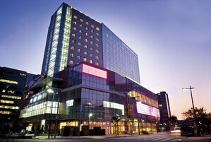 Un hotel moderno con fachada de vidrio, varios pisos y ventanas iluminadas.