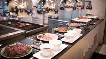 A buffet setup with various dishes, including meats and salads, and a grill with food being cooked.