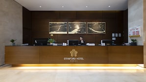 A reception desk at Stanford Hotel Seoul with a modern design, including a logo, a digital screen, and a plant. - Stanford Hotel Seoul (Seoul)