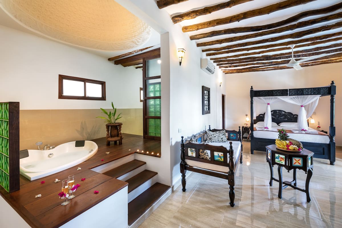 A bathroom with a bathtub, a wooden bench, and a small table with fruit.