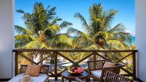 A balcony with wooden furniture, a fruit bowl, and a straw hat. - Next Paradise Boutique Resort (Pwani Mchangani)