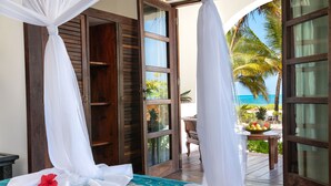 A room with a bed, a wooden door, and a view of the ocean. - Next Paradise Boutique Resort (Pwani Mchangani)