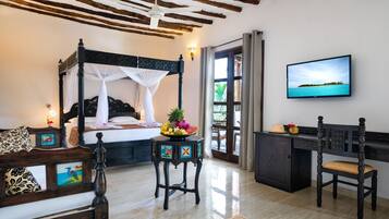 Relax in a serene bedroom with a four-poster bed, wooden desk, and scenic views on the TV.