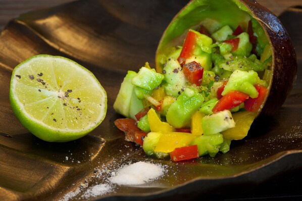 Un plat contenant des légumes coupés en dés et une demi-lime, le tout présenté sur une assiette sombre.