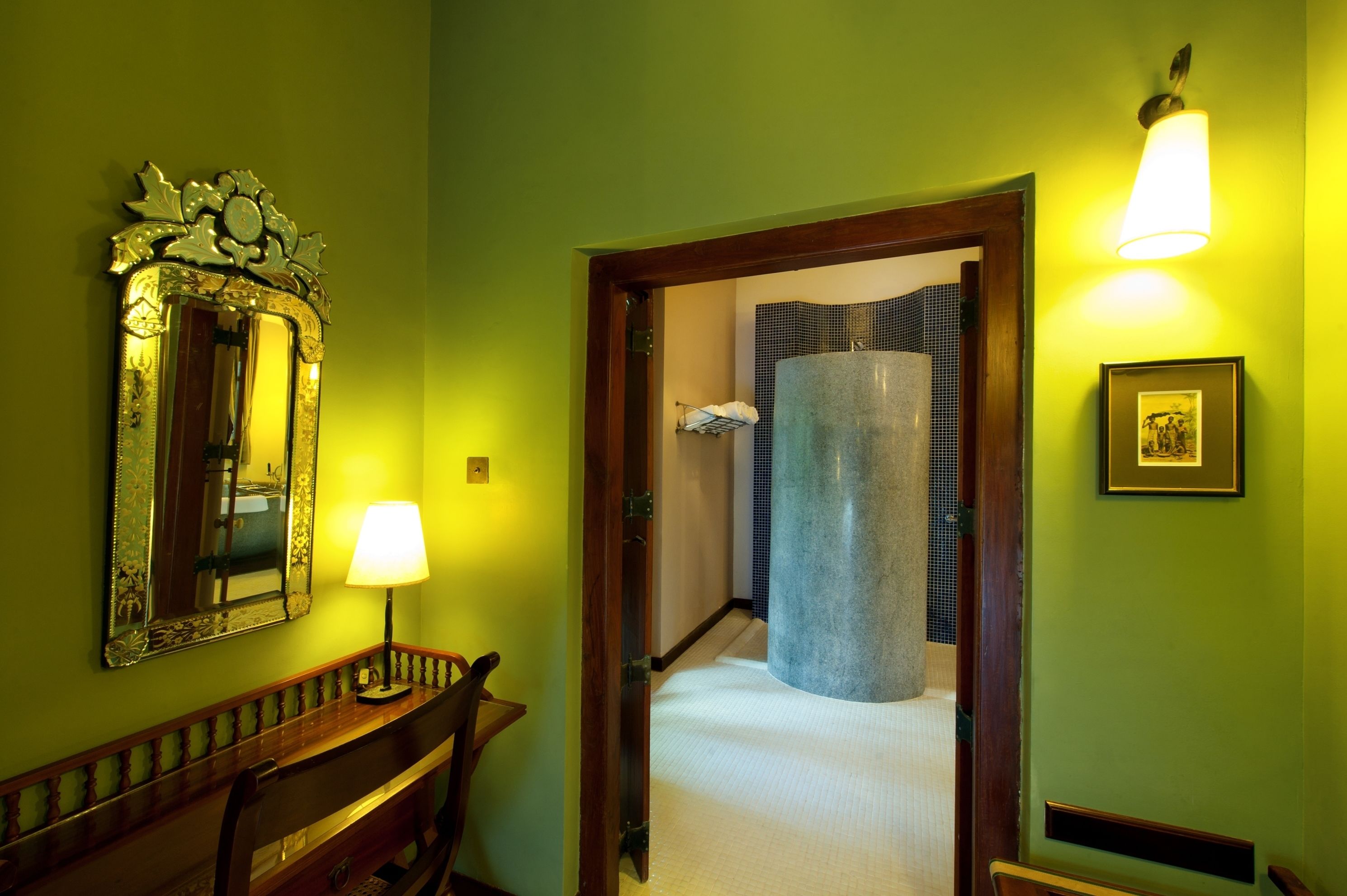 A hallway with a wooden bench, a mirror, a lamp, and a framed picture on the wall.