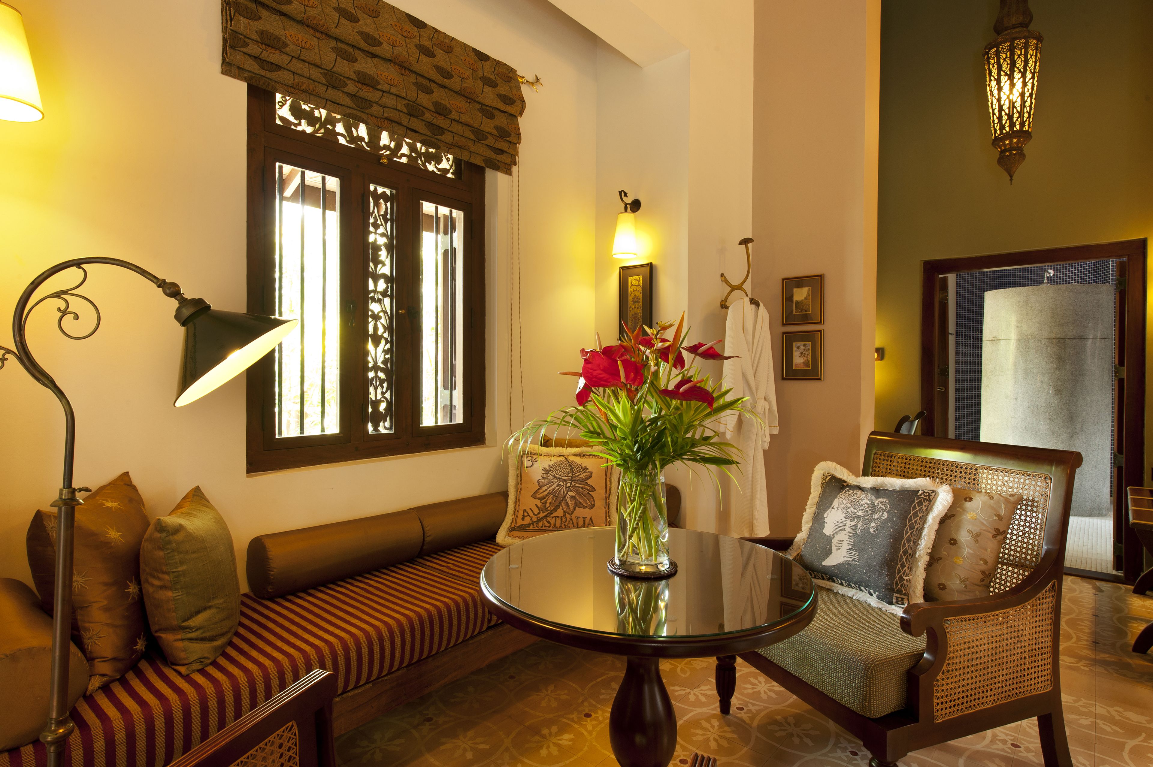 A cozy seating area with a round glass table, a sofa, and a chair with cushions.
