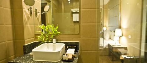 Un baño moderno con un espejo grande, un lavabo blanco y una planta en maceta.