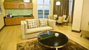 A modern living room with a sofa, a coffee table, and a dining area with chairs. - Goldberry Suites & Hotel Mactan (Lapu-Lapu)