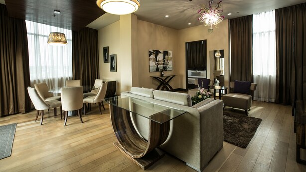 A modern living room with a glass coffee table, beige sofas, and a dining area with chairs. - Goldberry Suites & Hotel Mactan (Lapu-Lapu)