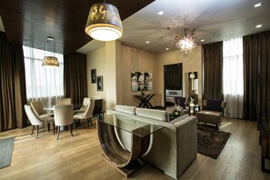 A modern living room with a glass coffee table, beige sofas, and a dining area with chairs. - Goldberry Suites & Hotel Mactan (Lapu-Lapu)