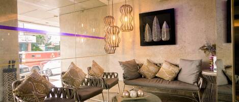 A modern interior with a sofa, chairs, a glass coffee table, and decorative lighting.