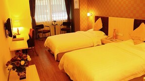 A hotel room with two beds, a desk, a chair, a small table, and a window with curtains. - Xiao Jia He (Chengdu)