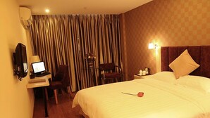 A hotel room with a bed, a desk with a computer, a chair, a lamp, and a curtain. - Xiao Jia He (Chengdu)