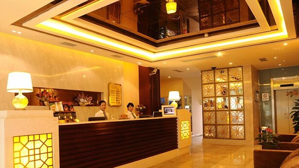 A hotel reception area with a modern design, featuring a reception desk, two receptionists, and a decorative wall with a geometric pattern. - Xiao Jia He (Chengdu)