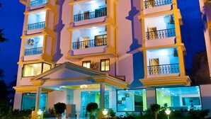 Un hôtel à plusieurs étages doté de balcons, d’une entrée couverte et d’une façade bien éclairée.