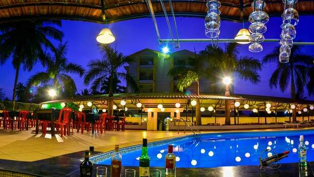 Un espace bar aménagé au bord de la piscine, avec une piscine, des tabourets de bar et des luminaires suspendus.