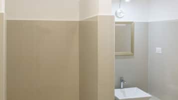 Een badkamer met een douche, wastafel en spiegel.