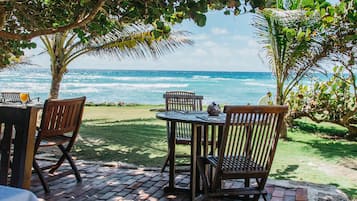 An outdoor seating area with tables and chairs, overlooking the ocean.