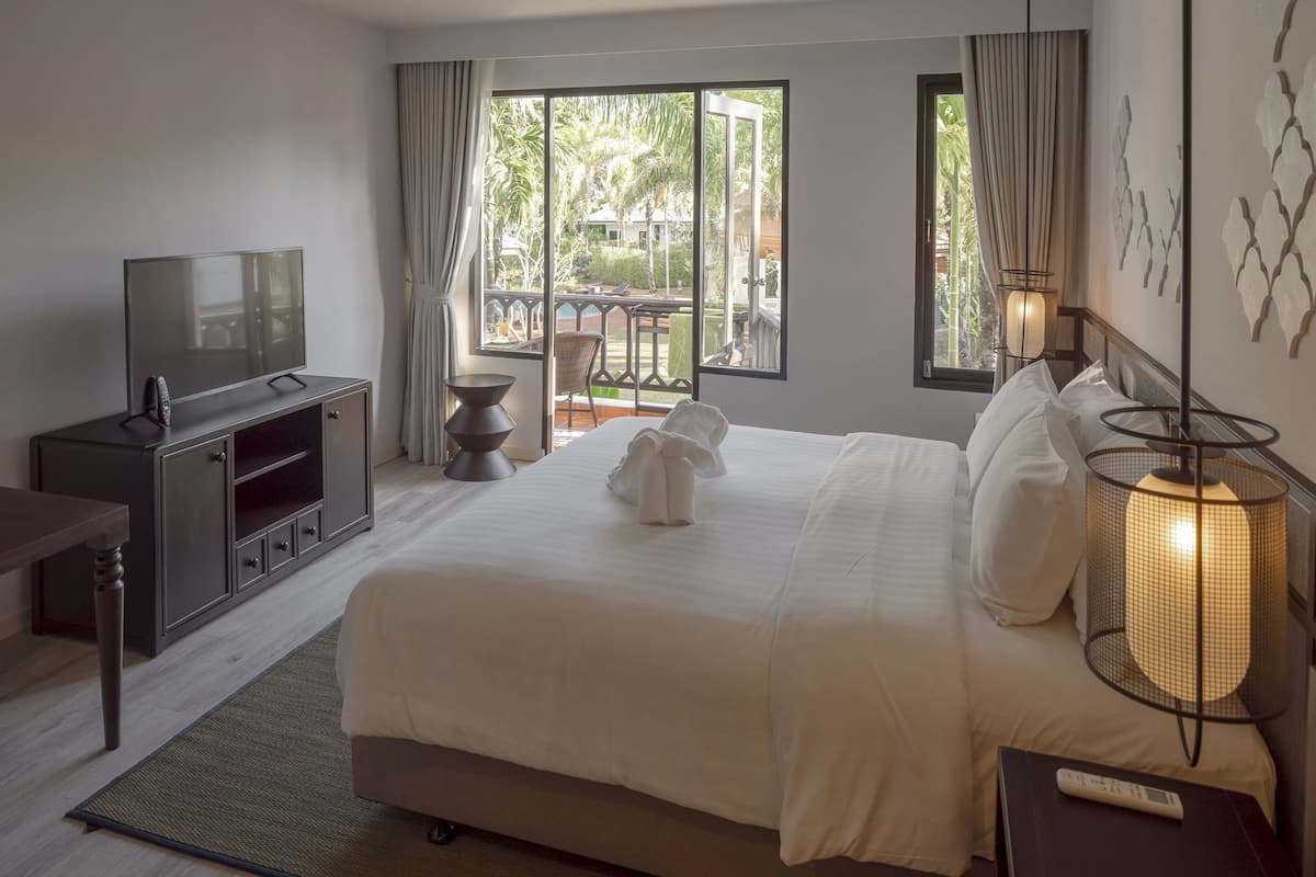 A hotel room with a bed, TV, and a view of the outdoors.