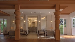 A spacious interior with wooden flooring, large wooden columns, and hanging pendant lights. - The Pe La Resort, Phuket (Kamala)