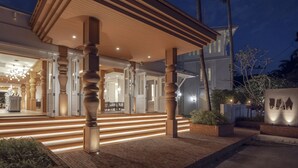 A modern building with a covered entrance, wooden columns, and a well-lit outdoor area. - The Pe La Resort, Phuket (Kamala)