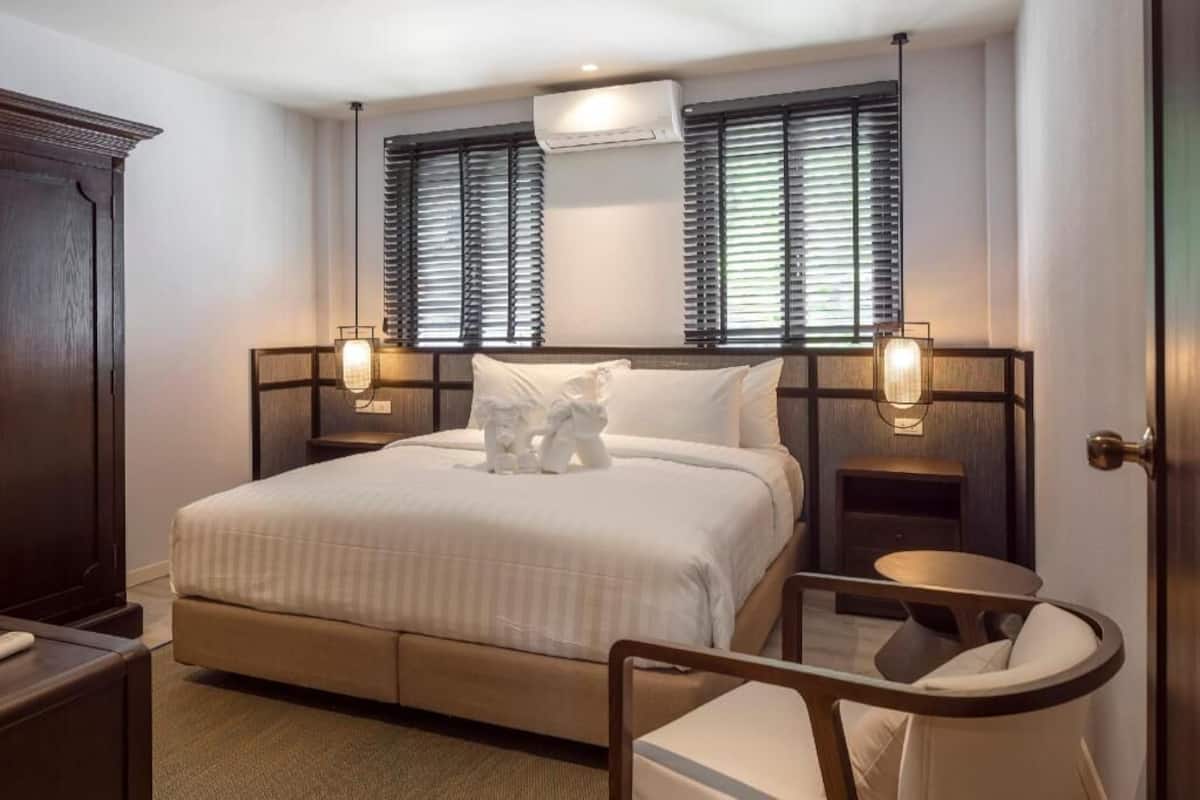 A hotel room with a large bed, two bedside tables, a small round table, and a wardrobe.