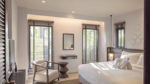 A modern hotel room with a large bed, a desk, a chair, and a small side table. - The Pe La Resort, Phuket (Kamala)