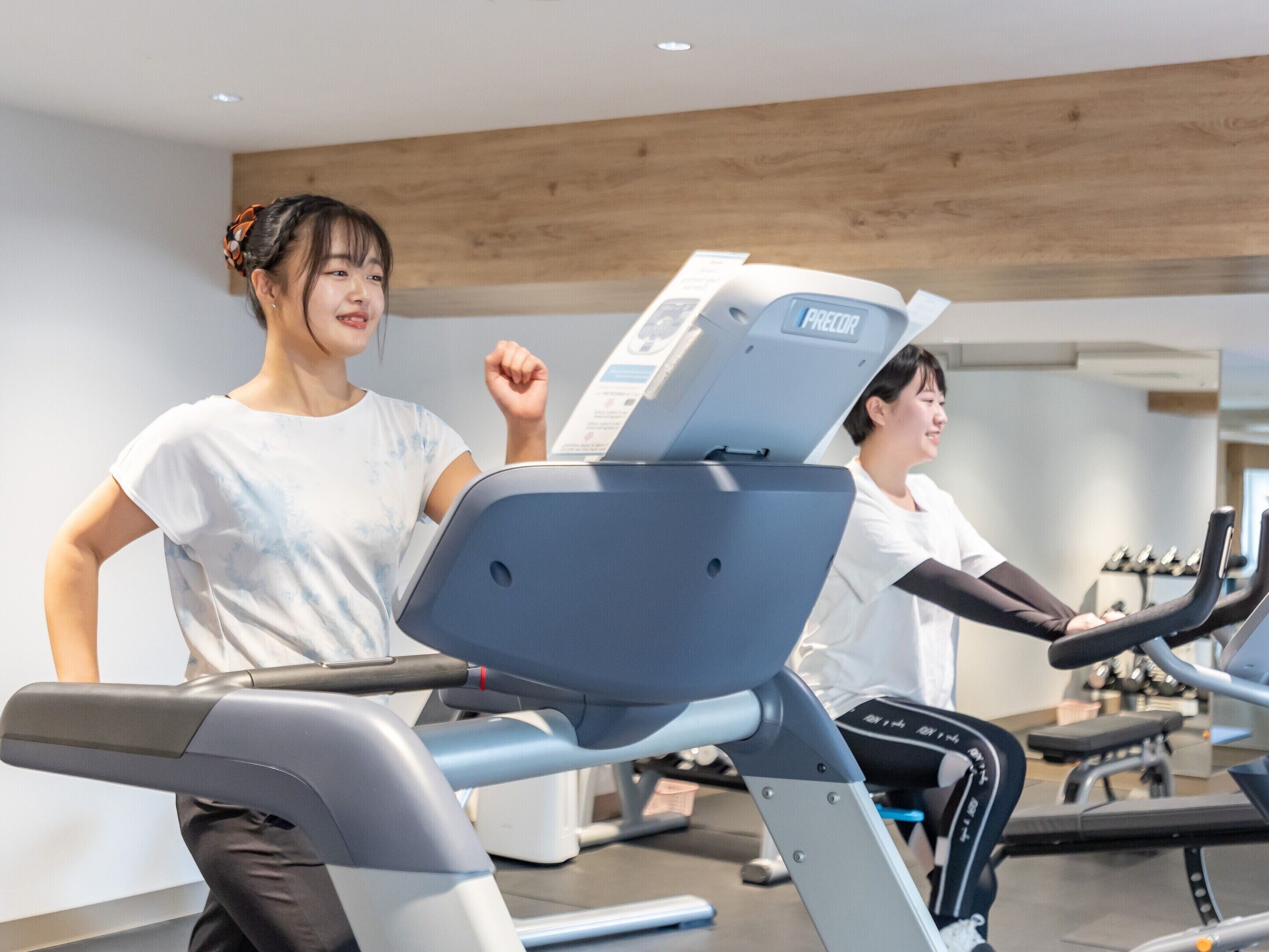 A gym with exercise equipment, including treadmills and a stationary bike, and a mirror on the wall.