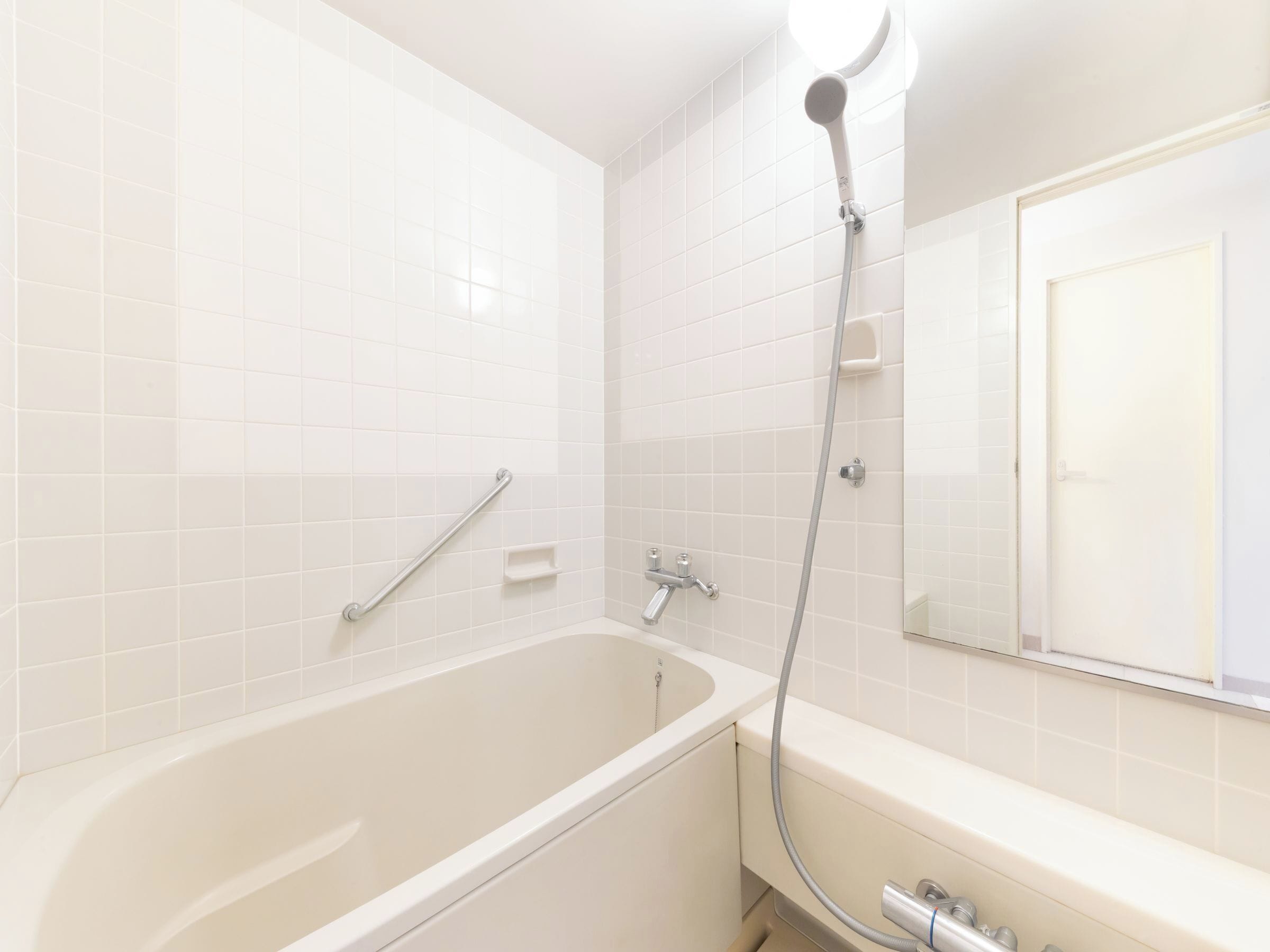 Un baño con bañera, ducha, barandilla y espejo.