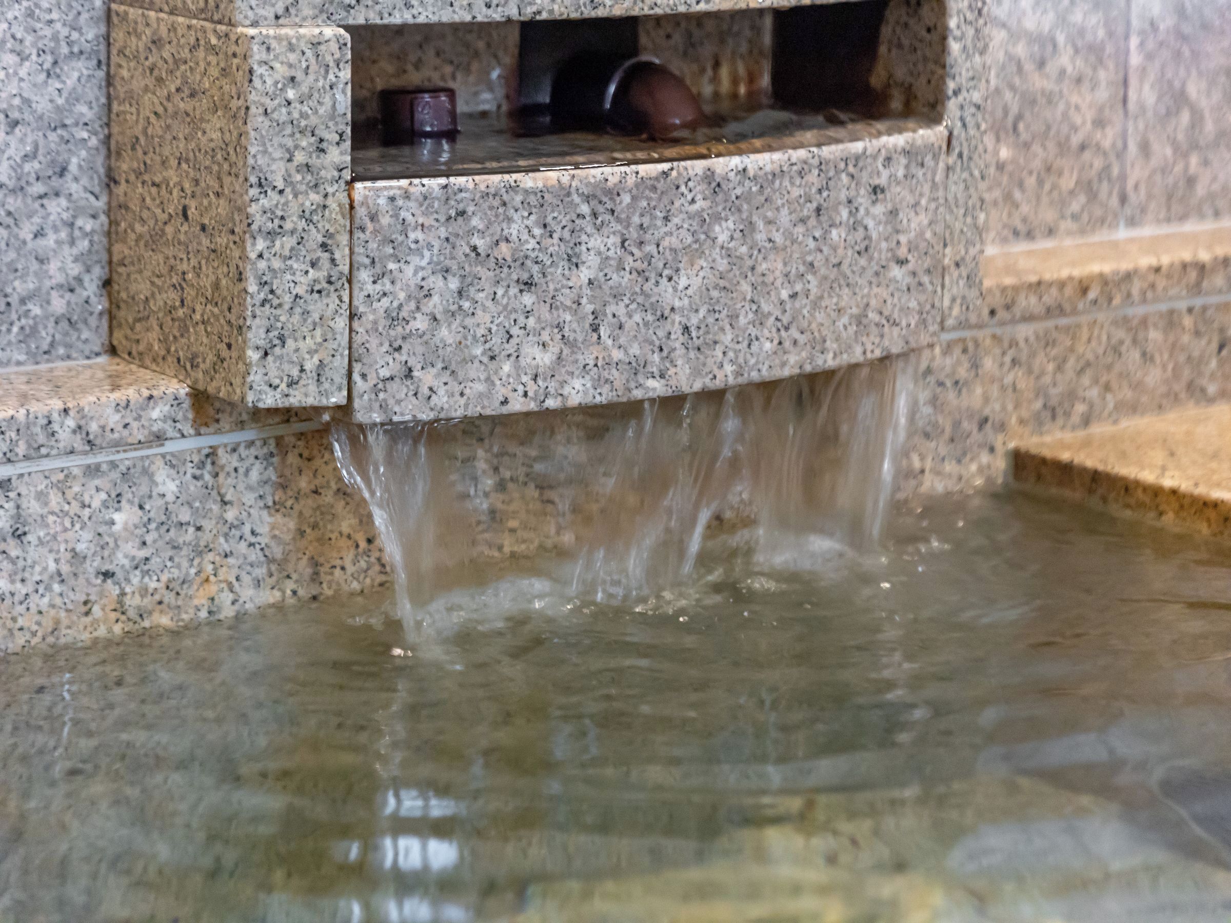 A water feature with a stone basin and a small shelf.