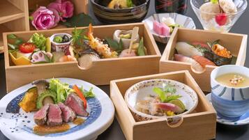 Variedad de platos japoneses en cajas y recipientes de madera, incluyendo sushi, sashimi y un tazón de sopa.