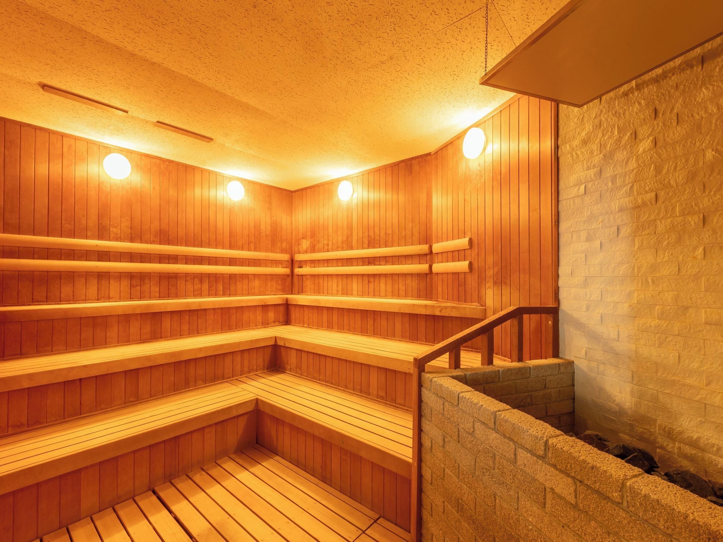 Sauna, jossa on puiset lauteet ja kiviseinä.