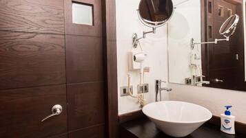 Un baño con puerta de madera, un lavabo blanco, un espejo y un secador de manos.