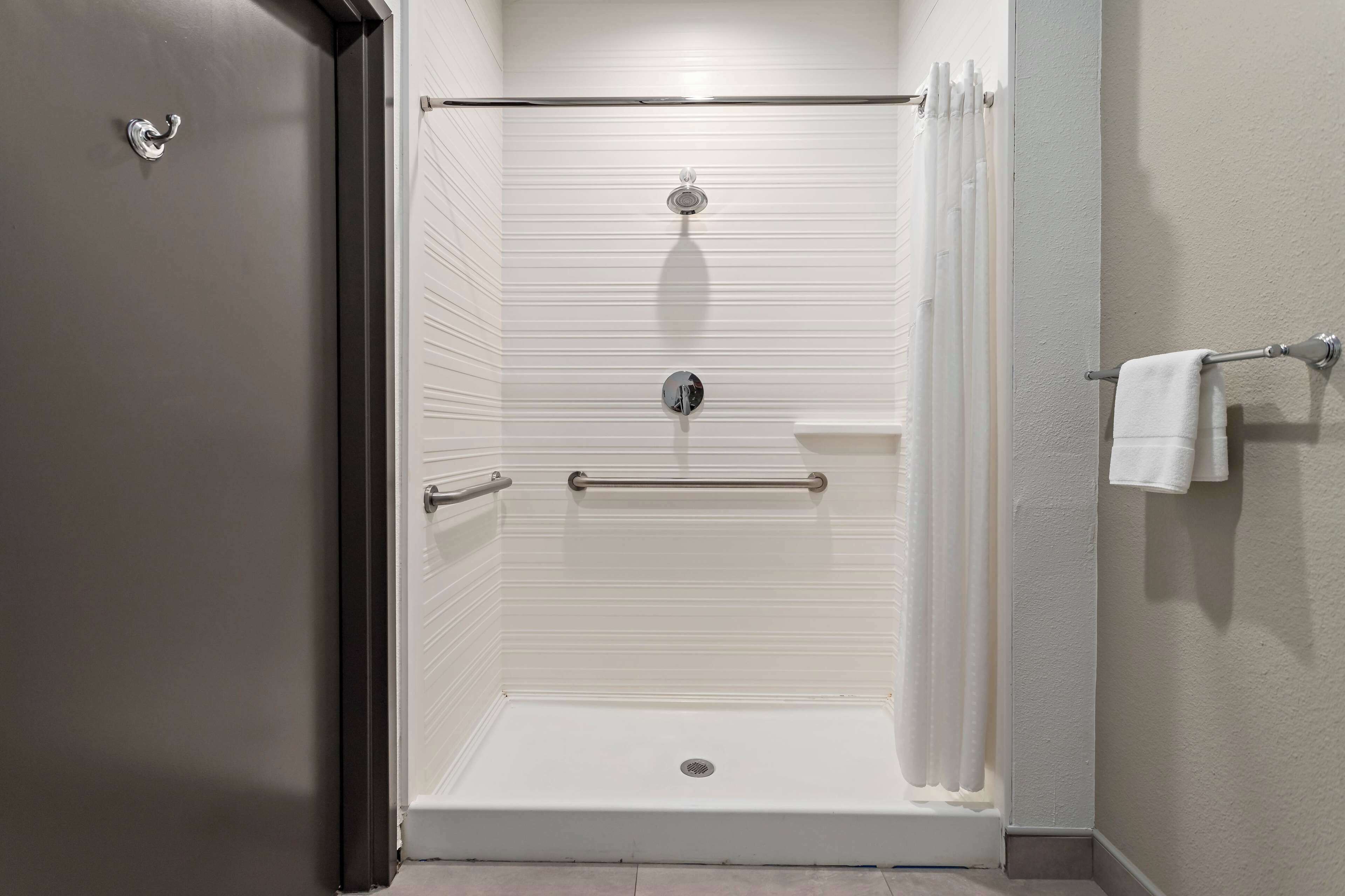 A walk-in shower with a grab bar, a towel rack, and a shower curtain.