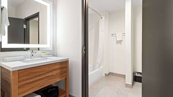 A modern bathroom with a wooden vanity, a large mirror, and a separate shower area.