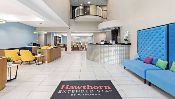 Un hall d’hôtel avec un comptoir d’accueil, un espace salon et un canapé bleu.
