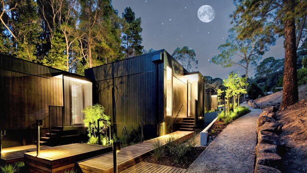 A modern cabin with a wooden exterior, a deck, and a pathway leading to the entrance. - Hepburn at Hepburn (Hepburn Springs)