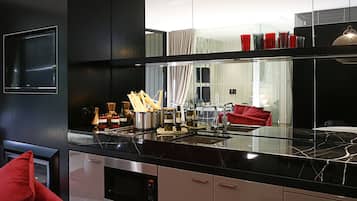 A modern kitchen with a black countertop, stainless steel appliances, and a red chair.